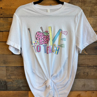 White t-shirt with colorful text and graphics on a wooden surface