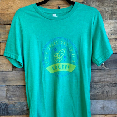 Green t-shirt with a logo on a wooden surface