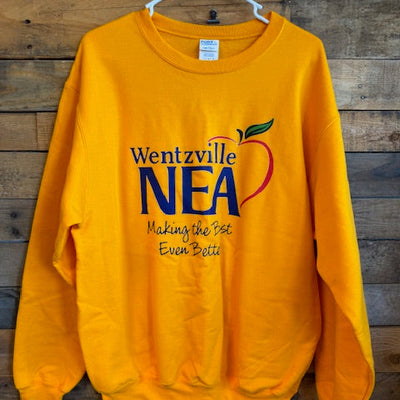 Yellow t-shirt with 'Wentzville NEA' logo on a wooden background