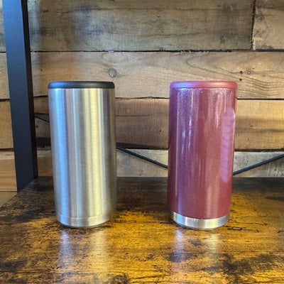 Two cylindrical metal objects, one pink and one silver, on a wooden surface.
