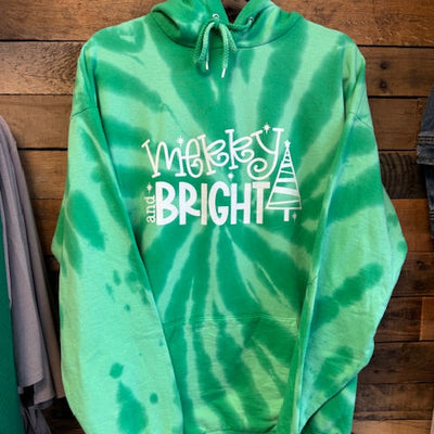 Green tie-dye hoodie with 'merry and Bright' text on a wooden surface