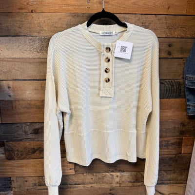 Beige corduroy shirt on a wooden surface with a visible brand tag.