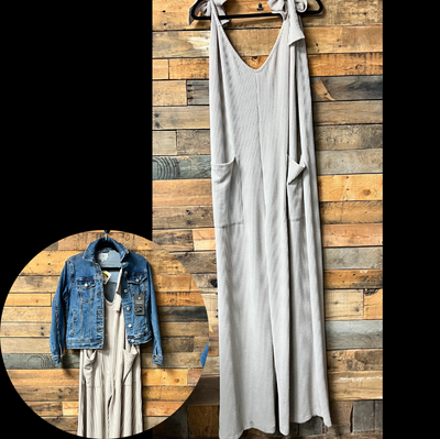 tank jumpsuit hanging on a wooden wall with a denim jacket