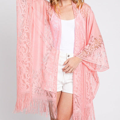 Woman wearing a pink lace kimono with fringe on a white background