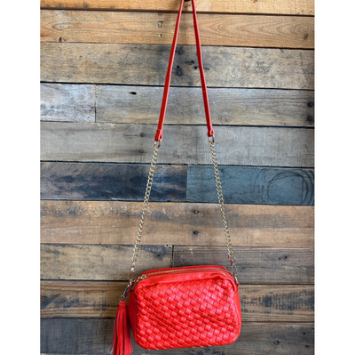Red woven handbag with a chain strap against a wooden background
