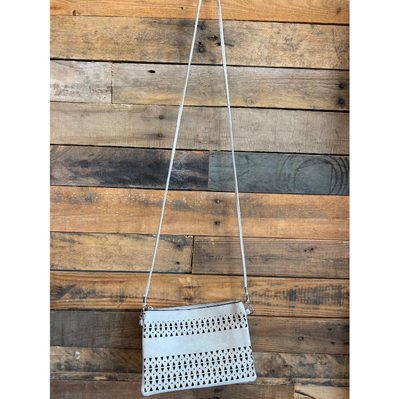 taupe crossbody bag with cut-out design against a wooden background